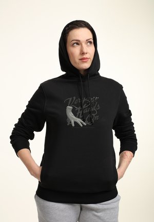 Sort hættetrøje med et frontgrafik, der læser "Very Hands On" i grå. Stoffet ser blødt ud; har en hætte med snor og ribbede cuffs.