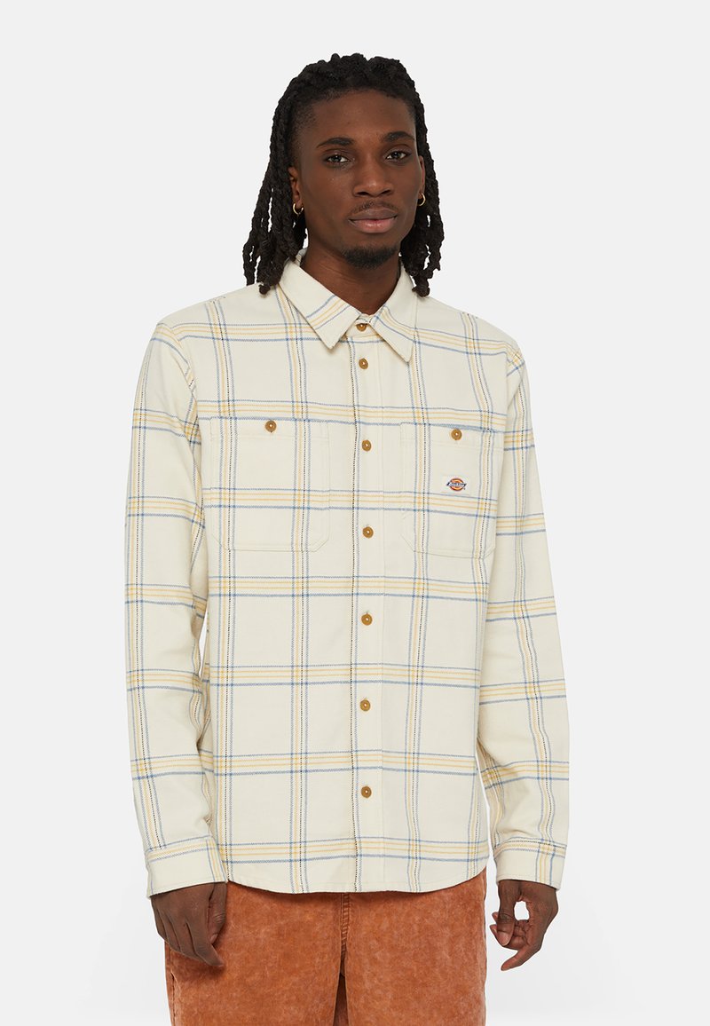 Camisa de cuadros de manga larga en crema, con cuadros azules y amarillos, cuello abotonado, dos bolsillos en el pecho y acentos de botón de metal.