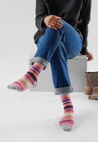 Calcetines multicolores con rayas anchas y estrechas en rosa, naranja, púrpura y crema. Mezcla de algodón con grosor medio y talón gris.