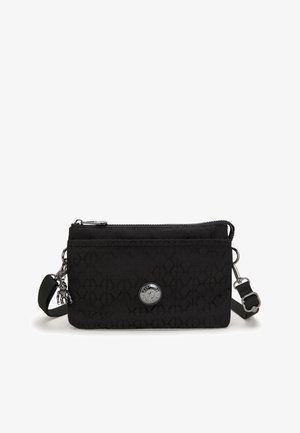 Black textured crossbody bag with adjustable strap, zip closure, front pocket, silver circular logo, and small monkey keychain charm.