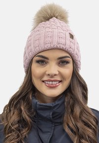 Gorro de punto rosa con un patrón texturizado y un gran pompón de piel sintética en la parte superior. Presenta una pequeña etiqueta de logo marrón en el lateral.