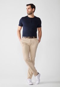 Marineblå kortærmet henley skjorte kombineret med beige bukser og hvide sneakers, med et brunt bælte og en afslappet pasform.