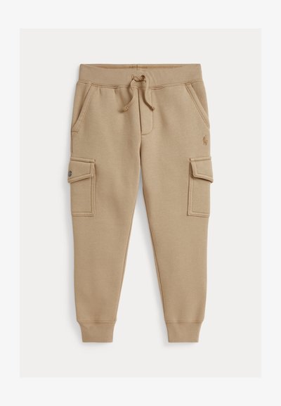 Calças de moletão bege feitas em mistura de algodão, com dois bolsos laterais e bolsos estilo cargo com fechos de pressão. Cintura elástica com cordão.