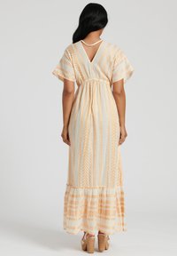 Robe maxi avec un dos en V, des manches courtes et une taille élastique. Tissu léger avec des rayures verticales orange et crème ainsi que des motifs géométriques.