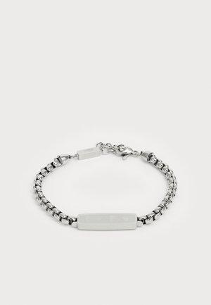 Hõbedane käevõru, millel on lingitud ahela disain ja keskel ristkülikuline plaat, millele on graveeritud erinevad simbolid. Reguleeritav lukk.