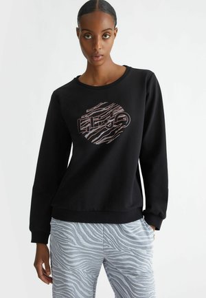 Felpa nera con colletto rotondo e maniche lunghe, presenta un design grafico rosa, abbinata a pantaloni a strisce zebra di colore blu chiaro.