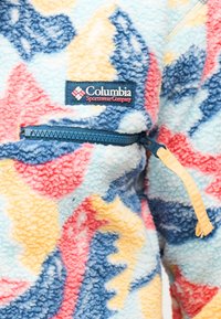 Χρωματιστό φλις μπουφάν με μπλε φερμουάρ και το λογότυπο της Columbia Sportswear Company στο στήθος, με αφηρημένα παστέλ μοτίβα σε κίτρινο, μπλε και ροζ.