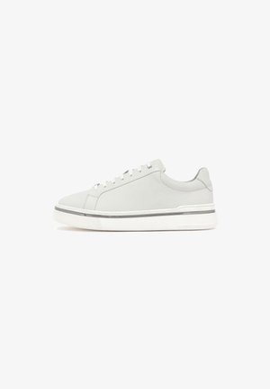 Weiße Low-Top-Sneaker mit weißen Schnürsenkeln, glattem Lederoberteil, dicker weißer Sohle mit grauem Streifen, fotografiert vor weißem Hintergrund.