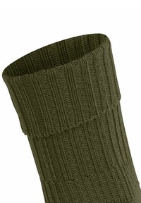 Prążkowana oliwkowa skarpetka z szerokim ściągaczem, z wyraźnym wzorem plecionki, leżąca na białym tle.