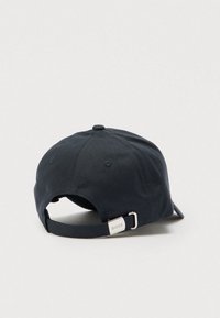 Tmavomodrá šiltovka s jednoliatou textúrou látky, nastaviteľným pásikom vzadu a kovovým akcentom s názvom značky.