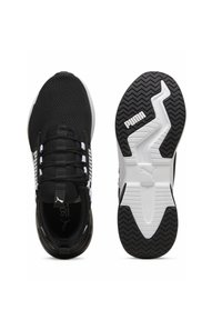 Baskets de sport noires avec une tige en mesh texturé, des accents blancs et une semelle en caoutchouc en zigzag. Elles disposent de lacets élastiques et d'un logo sur le côté.