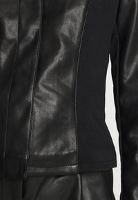 Czarna skórzana kurtka z teksturowanym panelem skórzanym i elastycznymi sekcjami materiałowymi. Gładkie wykończenie z dopasowanym krojem, ukazującym szwy i detale przeszycia.