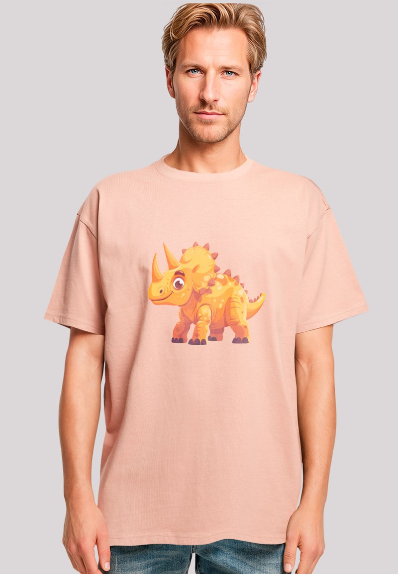 Light pink cotton t-shirt featuring a colorful cartoon triceratops graphic on the front. Loose fit with short sleeves and crew neck.