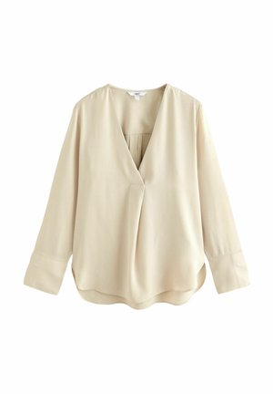 Beige bluse med lange ærmer og V-udskæring, skjult lukning foran, løs pasform og brede manchetter, vist mod en hvid baggrund.