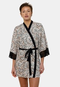 Kimono à motif floral en tissu doux, avec des bordures en dentelle noire sur les manches évasées, une ceinture noire, et un fond rose clair.