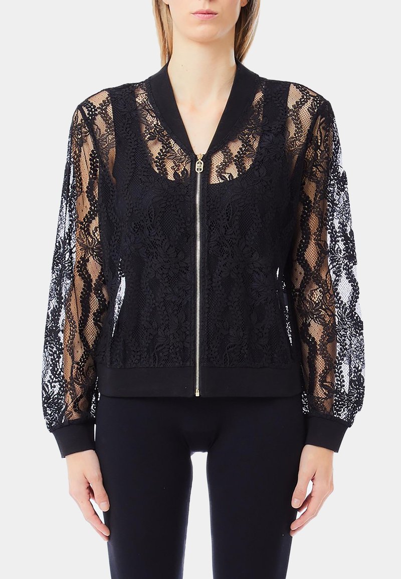 Giacca bomber nera con maniche in pizzo e zip frontale, caratterizzata da un corpo inferiore nero uniforme e polsini a coste sui polsi e sull'orlo.