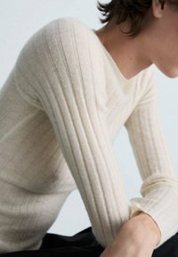 Hellbeige geripptes Strickpullover mit langen Ärmeln und taillierter Passform, mit feiner Textur und klassischem Rundhalsausschnitt.