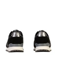 Baskets de sport noires avec tige en suede et mesh, accents réfléchissants argentés au niveau du talon, semelle extérieure en caoutchouc et semelle intermédiaire blanche. Design minimaliste.