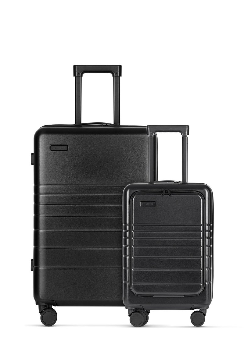 Zwart hard-shell kofferset met een horizontaal ribbelontwerp. Bevat een grote koffer en een kleinere handbagage, beide met uitschuifbare handvatten en wielen.