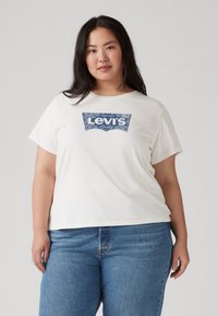 Λευκό βαμβακερό μπλουζάκι με μπλε λογότυπο Levi's. Κοντά μανίκια και άνετη εφαρμογή. Συνδυάζεται με μπλε τζιν, ολοκληρώνοντας την καθημερινή εμφάνιση.