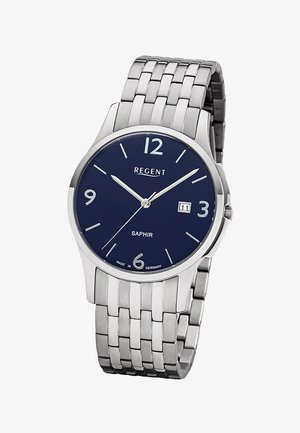 Montre-bracelet en métal argenté avec cadran bleu marine, chiffres blancs, affichage de la date à 3 heures, et bracelet métallique à maillons.