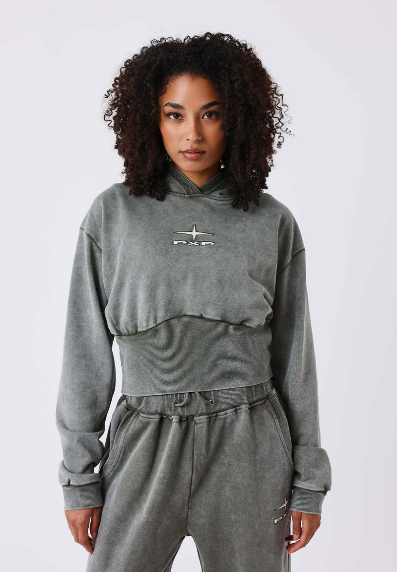 Groene cropped hoodie met lange mouwen, voorzien van ribgebreide boorden en een logodetail. Gecombineerd met bijpassende lose-fit sweatpants in een vergelijkbare kleur.