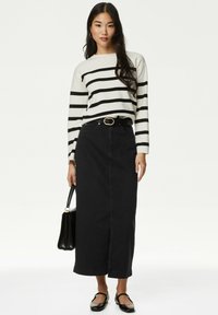 Pull en tricot rayé crème et noir, associé à une jupe en denim noir taille haute. Comprend également des ballerines noires et un sac à main noir.