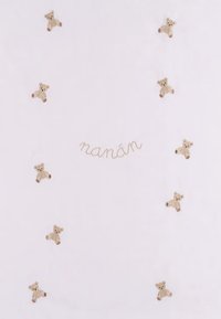 Couverture en coton rose pâle avec des motifs de teddy bear brodés et le mot "nanán" en fil beige, dotée d'une texture douce.