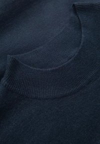 Navyblauer Pullover im Nahaufnahme, mit einem runden, gerippten Kragen und glatter Textur, die das Strickmuster des Stoffes hervorhebt.