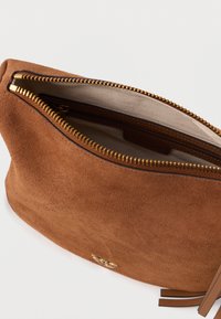 Καφέ σουέτ θήκη με χρυσό φερμουάρ. Μαλακή υφή, στρογγυλή μορφή και ορατή εσωτερική τσέπη. Διαθέτει διακοσμητικό λογότυπο και καφέ δερμάτινες λεπτομέρειες.