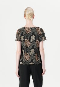Maglietta a maniche Corte con base nera caratterizzata da motivi astratti texturizzati in marrone, oro e crema. Taglio dritto, vestibilità comoda.