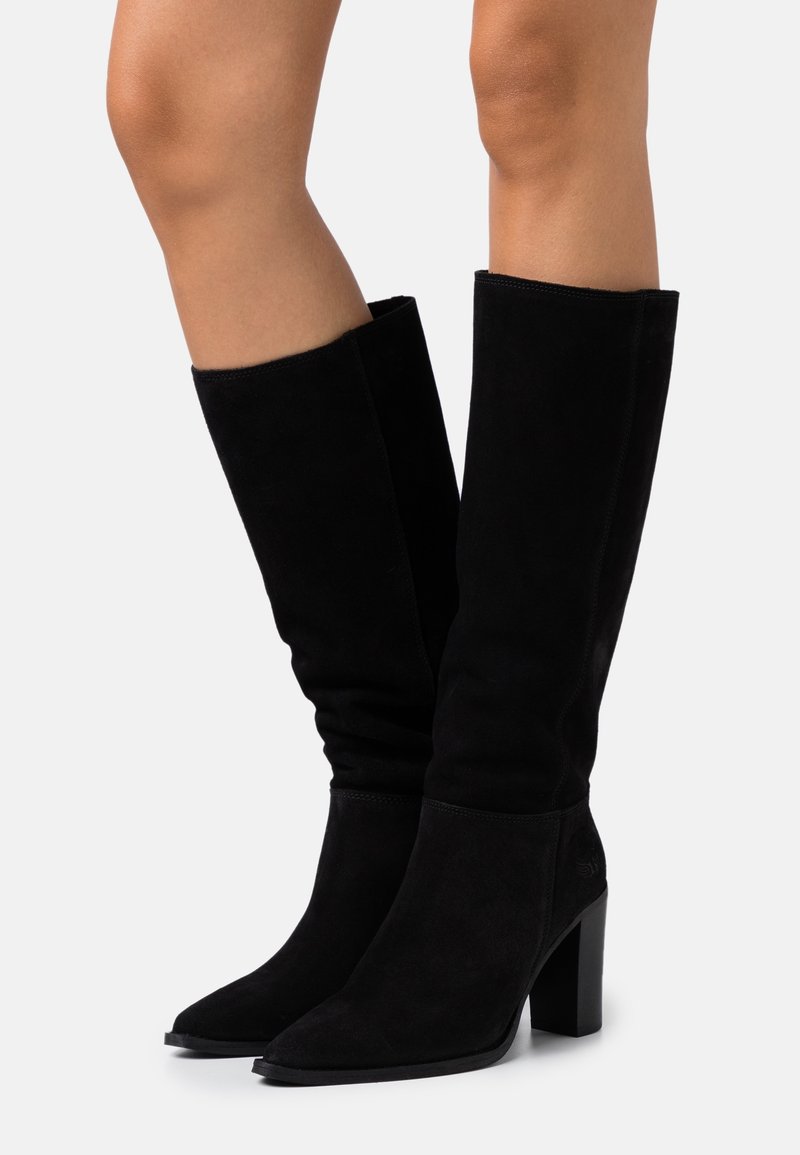 Bottes hautes en daim noir jusqu'au genou avec un bout pointu et un talon bloc. Le design présente une texture lisse et un minimum de détails.