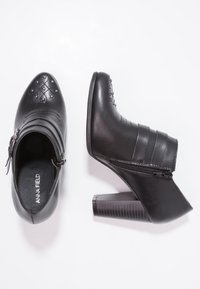 Botines negros con punta afilada, de cuero texturizado con acentos de costura, cremallera lateral y un tacón grueso y con patrón.