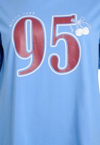 Lyseblå t-shirt med stort vinrødt "95" grafik, teksten "Since 1995" ovenover og kirsebærillustrationer med hvide detaljer. Glat bomuldsstof.