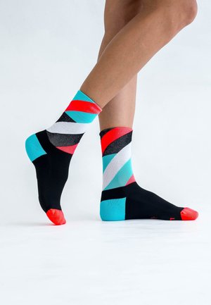 Black socks with vibrant diagonal stripes in red, light blue, white, and grey, featuring a red toe cap and contrasting heel.