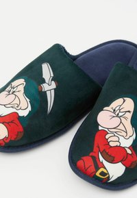 Gröna sammetsskor med tecknad karaktärsdesign av en arg dvärg, med blå foder och en strukturerad yta.