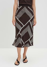 Gonna midi marrone con strisce diagonali bianche e motivi a diamante. Realizzata in un tessuto morbido, presenta un orlo svasato e una vita elastica.