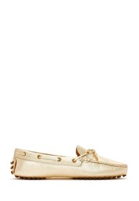 Mocassin en cuir doré clair avec semelle en caoutchouc cloutée, lacet décoratif autour du talon et nœud noué sur le dessus.