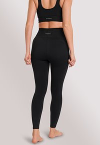 Schwarze Sportleggings und passendes Crop-Top aus strukturiertem Material mit gerippten Akzenten an der Taille. Langdesign.