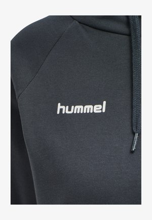 Close-up van een donkergrijze hoodie met wit "hummel" logo op de borst en een gevlochten trekkoord aan de rechterkant.