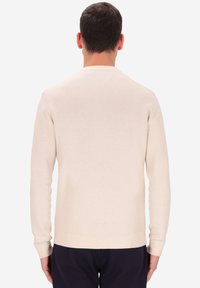 Maglione a maglia color crema con maniche lunghe, scollo rotondo e orlo a coste. Design semplice, realizzato in un morbido tessuto testurizzato.