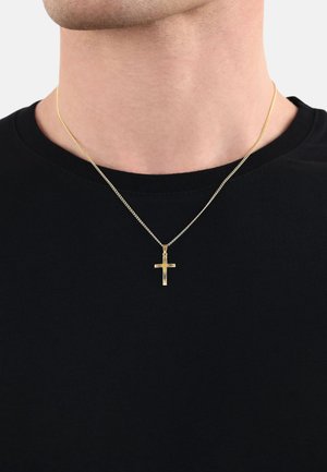 Collana a catena oro con pendente a croce verticale, esposta su una maglietta nera, caratterizzata da superfici lisce e maglie sottili.