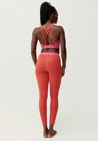 Roze sportbeha met kruisende bandjes en bijpassende hoge leggings in een gradient van licht naar donker roze. Zacht, rekbare stof.