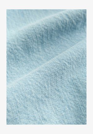 Lys blå denimstof med en glat tekstur, der har et klassisk twillvævningsmønster. Synlige lette variationer i farve og skygge.