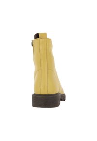 Bottine en cuir jaune avec une fermeture éclair sur le côté, semelle en caoutchouc noir texturé et détails de couture minimaux à l'arrière.