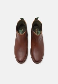 Bottines en cuir marron avec une surface lisse, des panneaux latéraux élastiques et des languettes de tirage. Détails surpiqués et design à bout rond.