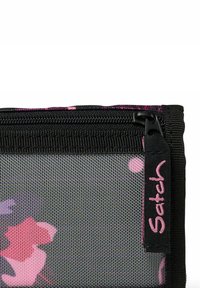 Borsa a rete nera con motivo floreale in tonalità di rosa e viola. Presenta una cerniera nera e un'etichetta con il logo "Satch".