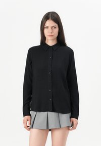 Zwarte lange mouwen knoopshirt met een puntige kraag, gemaakt van soepele stof, met een rechte snit en subtiele ruitpatroon.