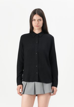 Camisa de botones negra de manga larga con cuello en punta, hecha de un tejido suave, con corte recto y una sutil textura de cuadros.