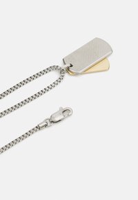 Metall hundetagskjede med en teksturert sølv- og gullpendant, med en fin kjede og en lås som er merket "BOSS".